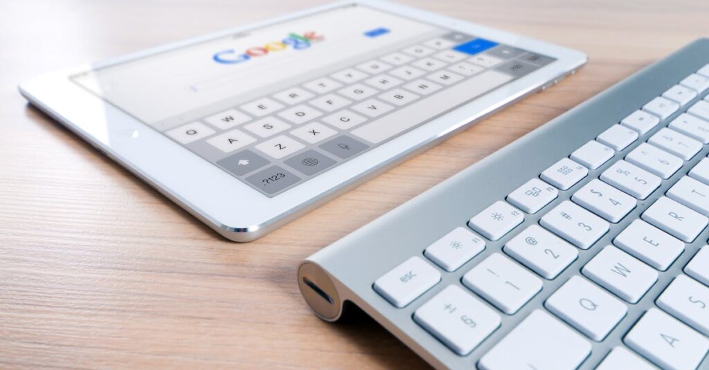 A modern tablet displaying a search engine logo next to a wireless keyboard on a wooden desk.